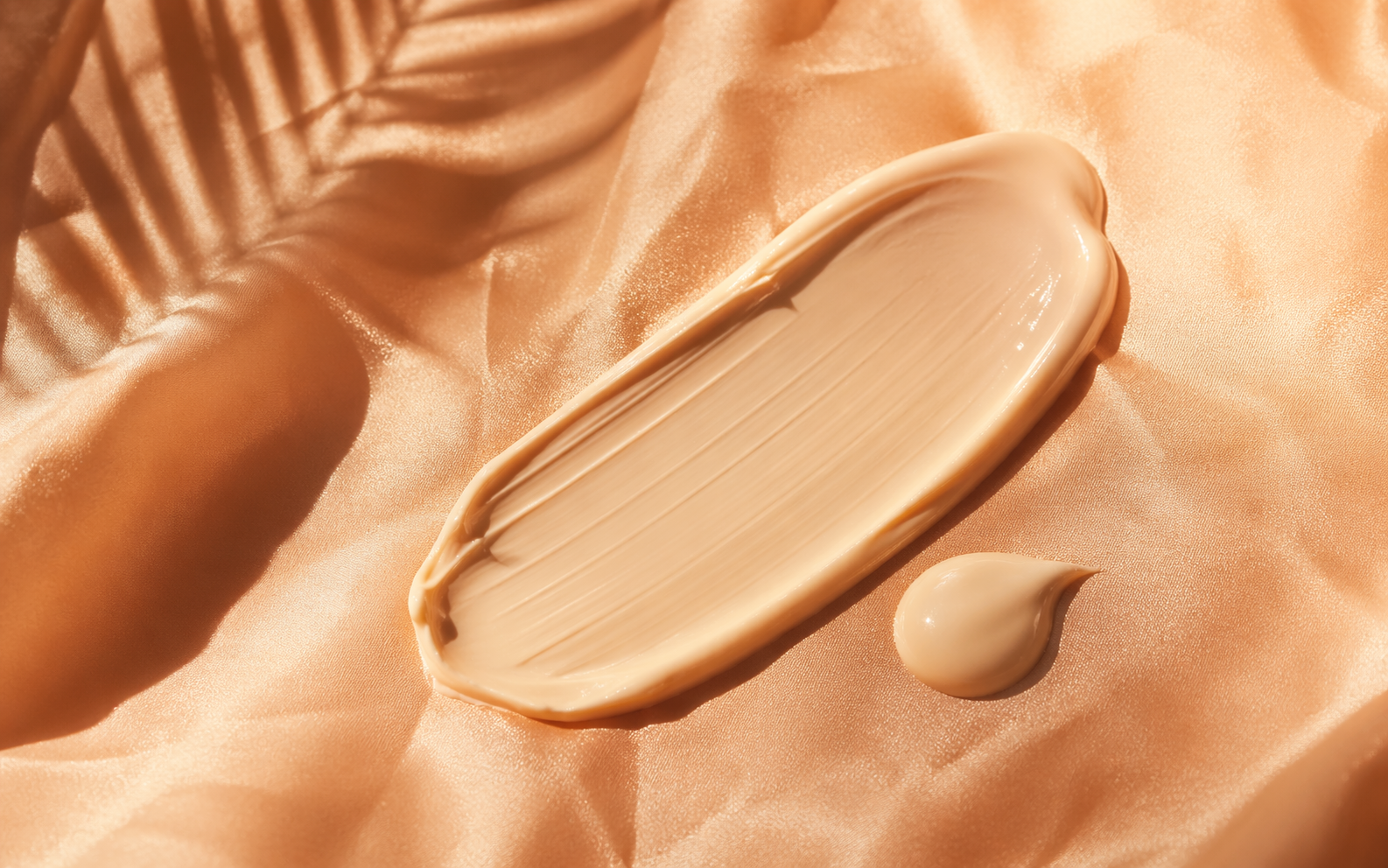 Creamy tinted sunscreen swatch on peach silk in golden-hour light